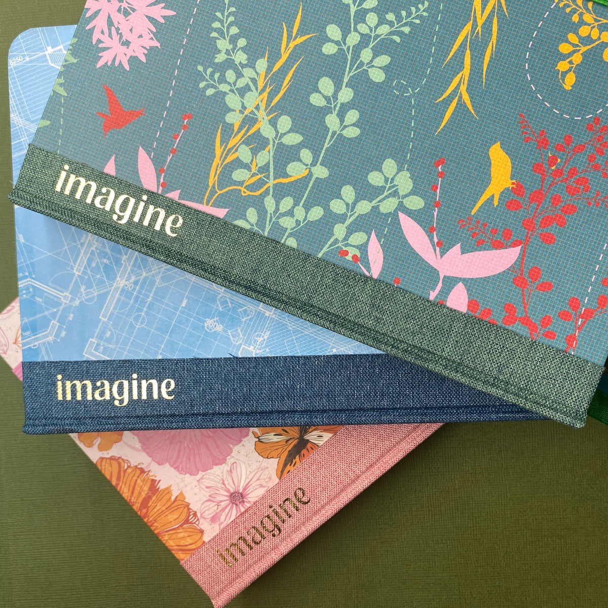 Three Imagine handmade journals notebooks with floral designs and 'imagine' branding on a green background curious owl books Toowoomba 